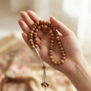 Hand holding sandalwood tasbeeh 100 beads with natural fragrance